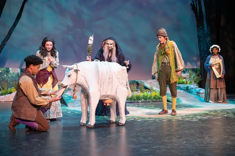 students performing on stage with a fake cow