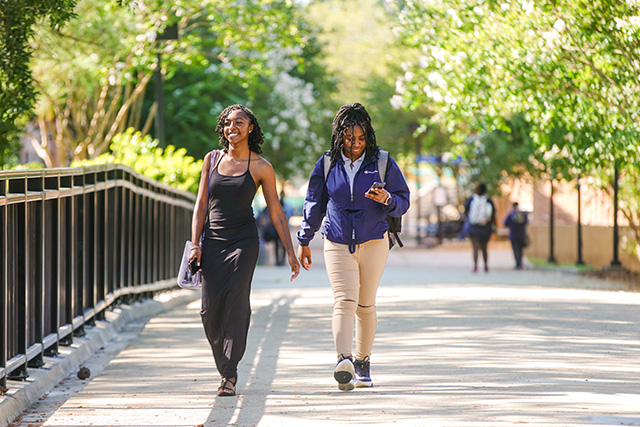 two female students walking across a bridge