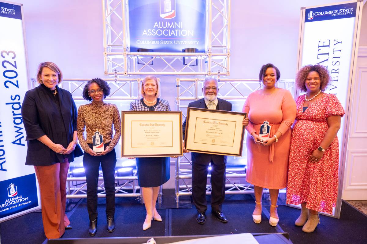 several men and women standing and holding two awards