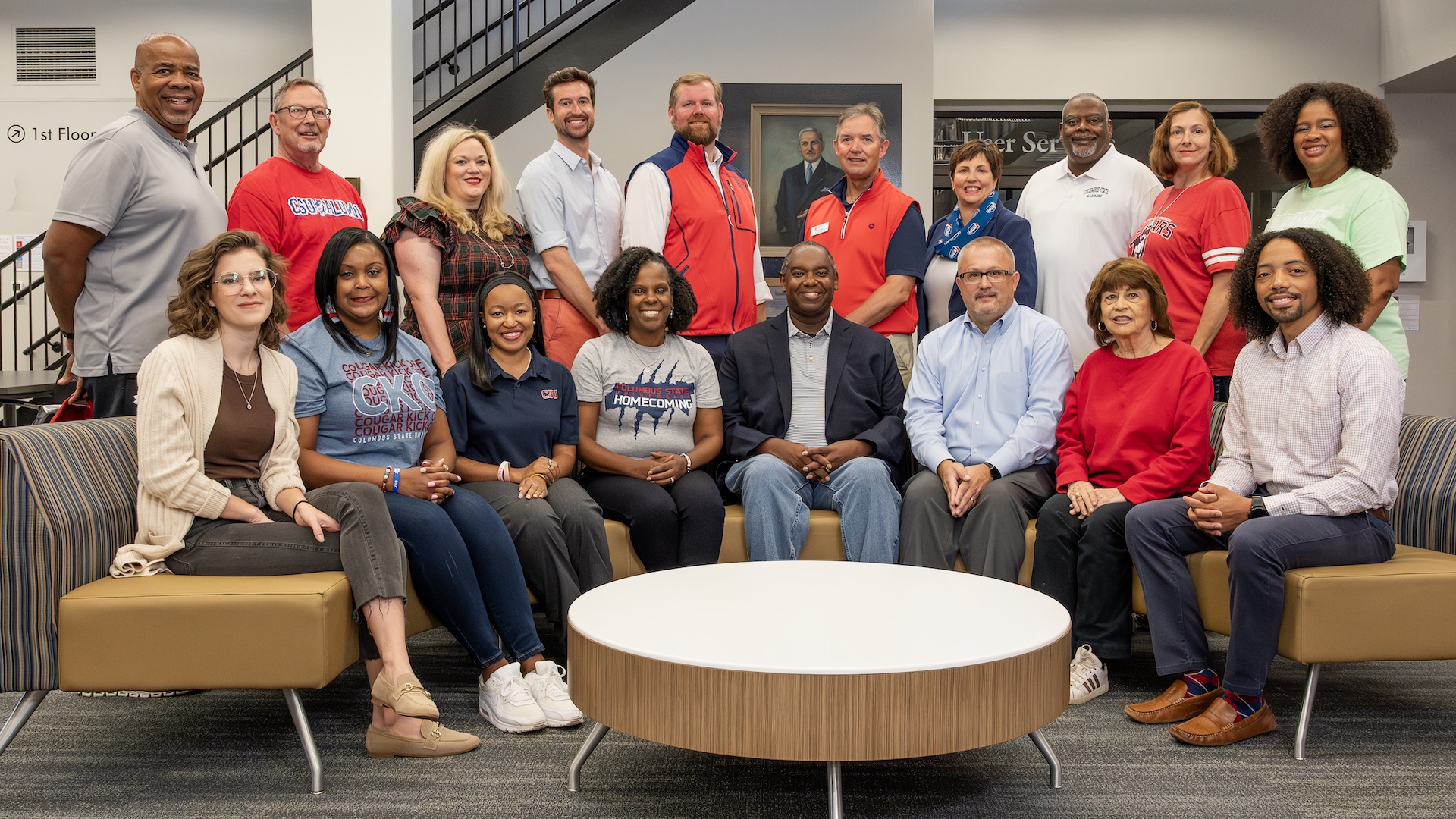 a large group of men and women standing and sitting, facing the camera