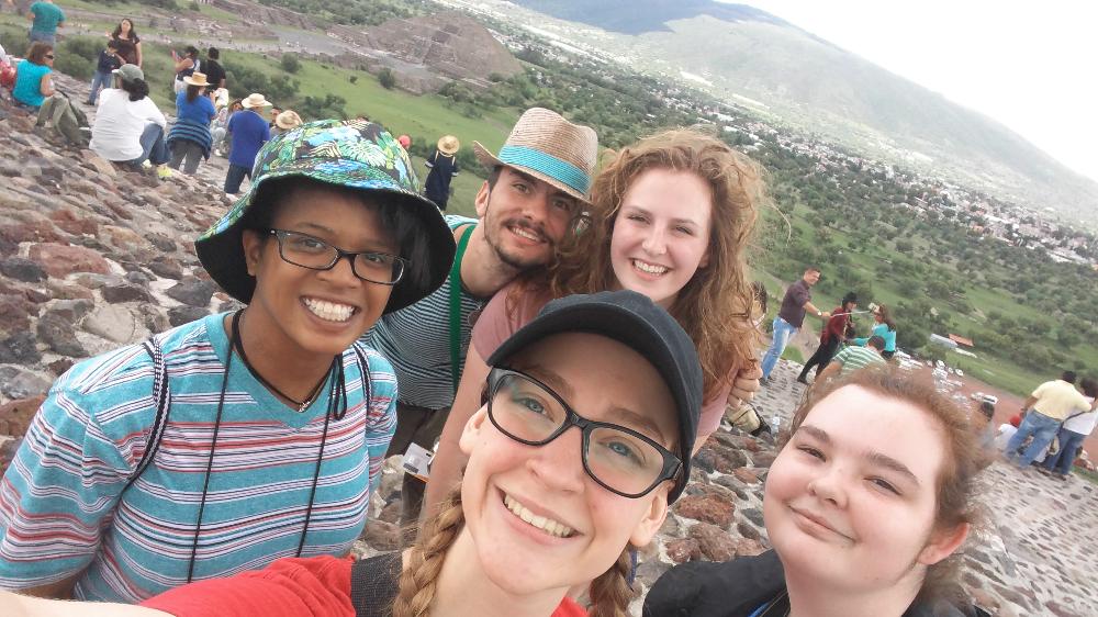 Five study abroad students with a pyramid behind in the distance